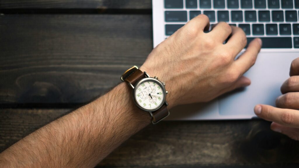 Tijd besparen ondernemers door efficiënt werken op laptop met horloge zichtbaar tijdens werkdag