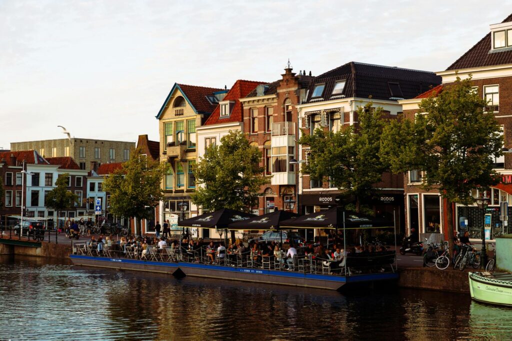 Terras aan gracht met mensen en historische huizen in Nederlandse stad