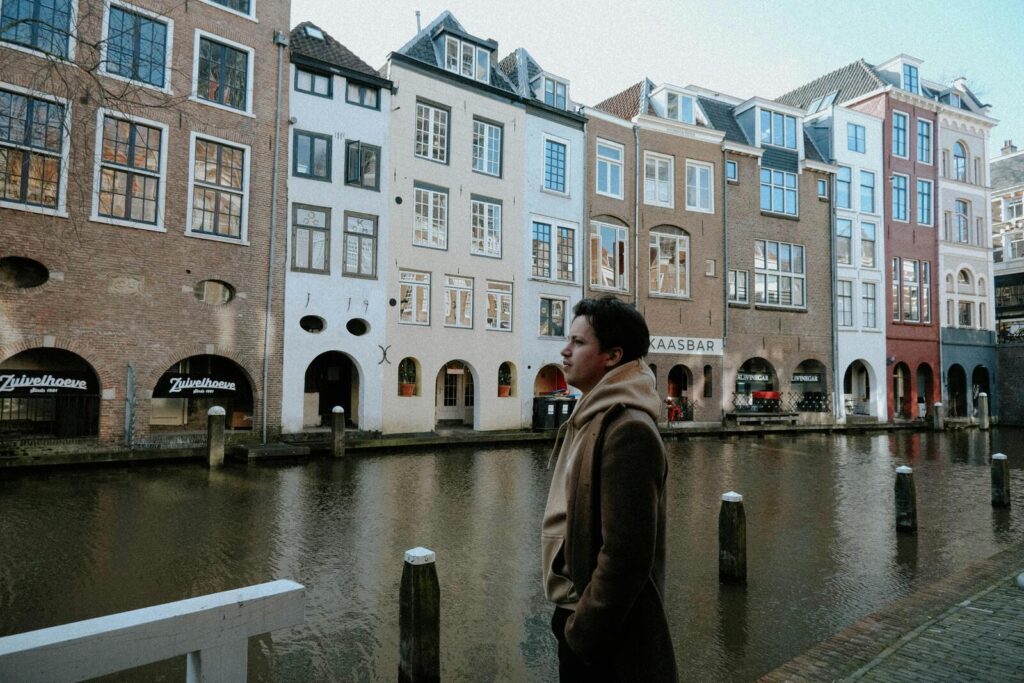 Man staat langs gracht in Utrecht met rij historische gebouwen op de achtergrond