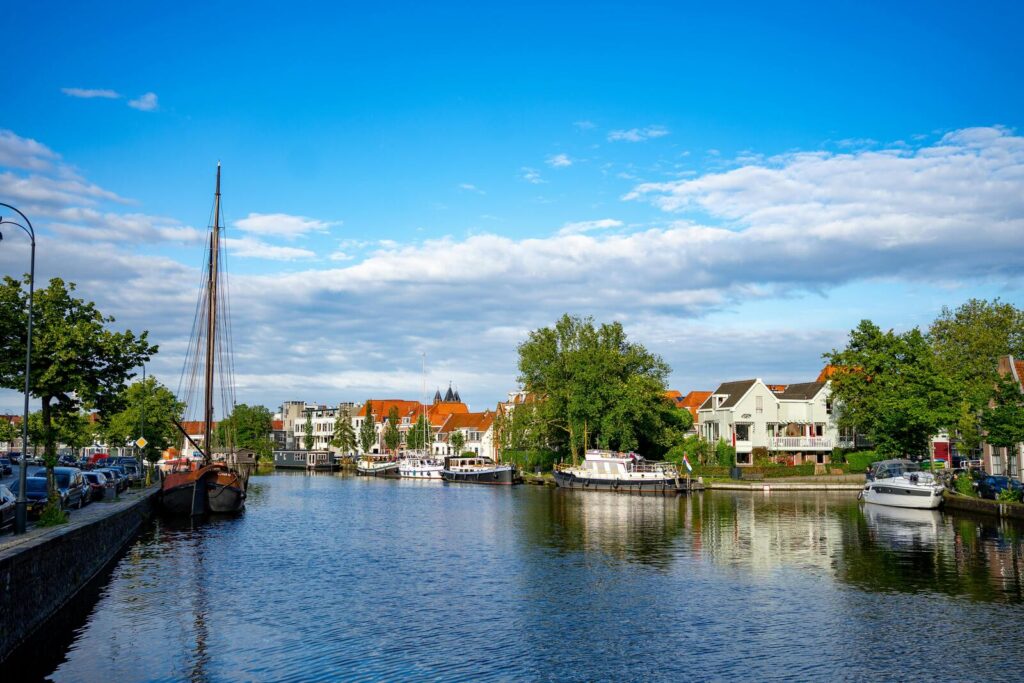 Gracht in Haarlem met boten en huizen langs het water onder blauwe lucht