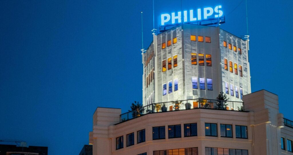 Philips gebouw in Eindhoven verlicht in de avond met logo op het dak