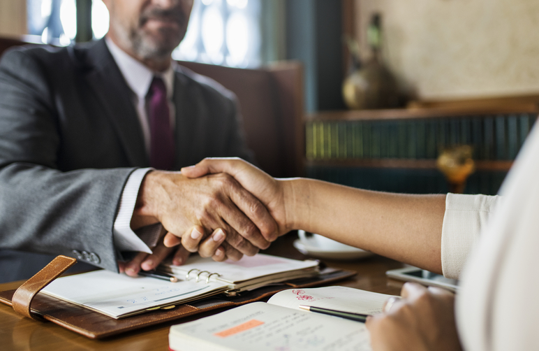 Notaris schudt hand tijdens adviesgesprek over notarisdiensten voor particulieren.