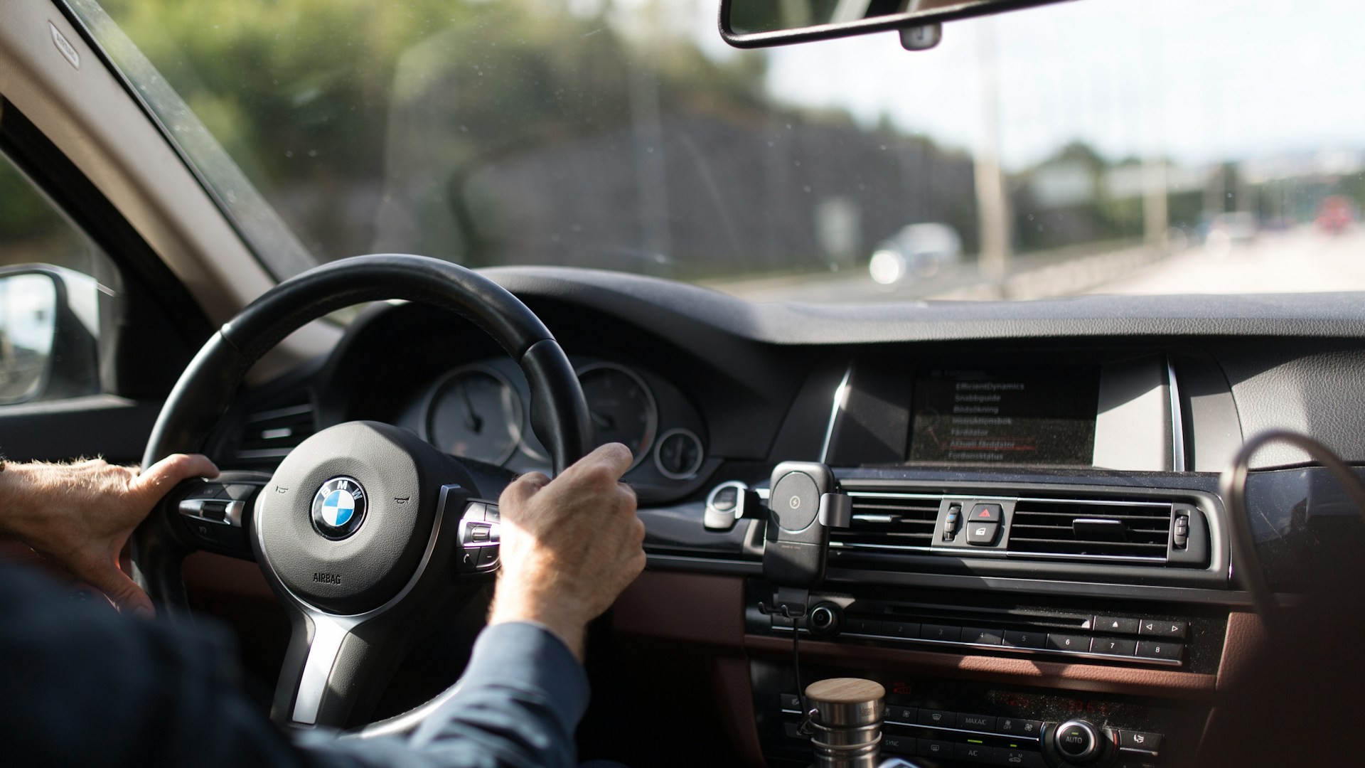 Bestuurder met handen aan het stuur tijdens een autorit – tips om te slagen voor je rijexamen